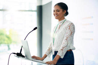 Confident woman presenting speech at podium with mic